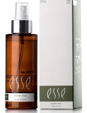 A bottle of Esse Biome Mist with a silver spray nozzle, housed in a brown container, is positioned beside its light green and white box package. Both the bottle label and the box prominently feature the brand name "Esse" along with the product description "Biome Mist." Additionally, the box is adorned with scientific graphics.