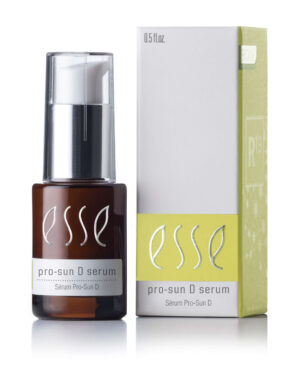 A small brown bottle of Esse Pro-Sun D Serum, featuring a white pump dispenser, stands next to its green and white packaging box which displays the product name and additional text. The bottle contains 0.5 fl oz of serum.