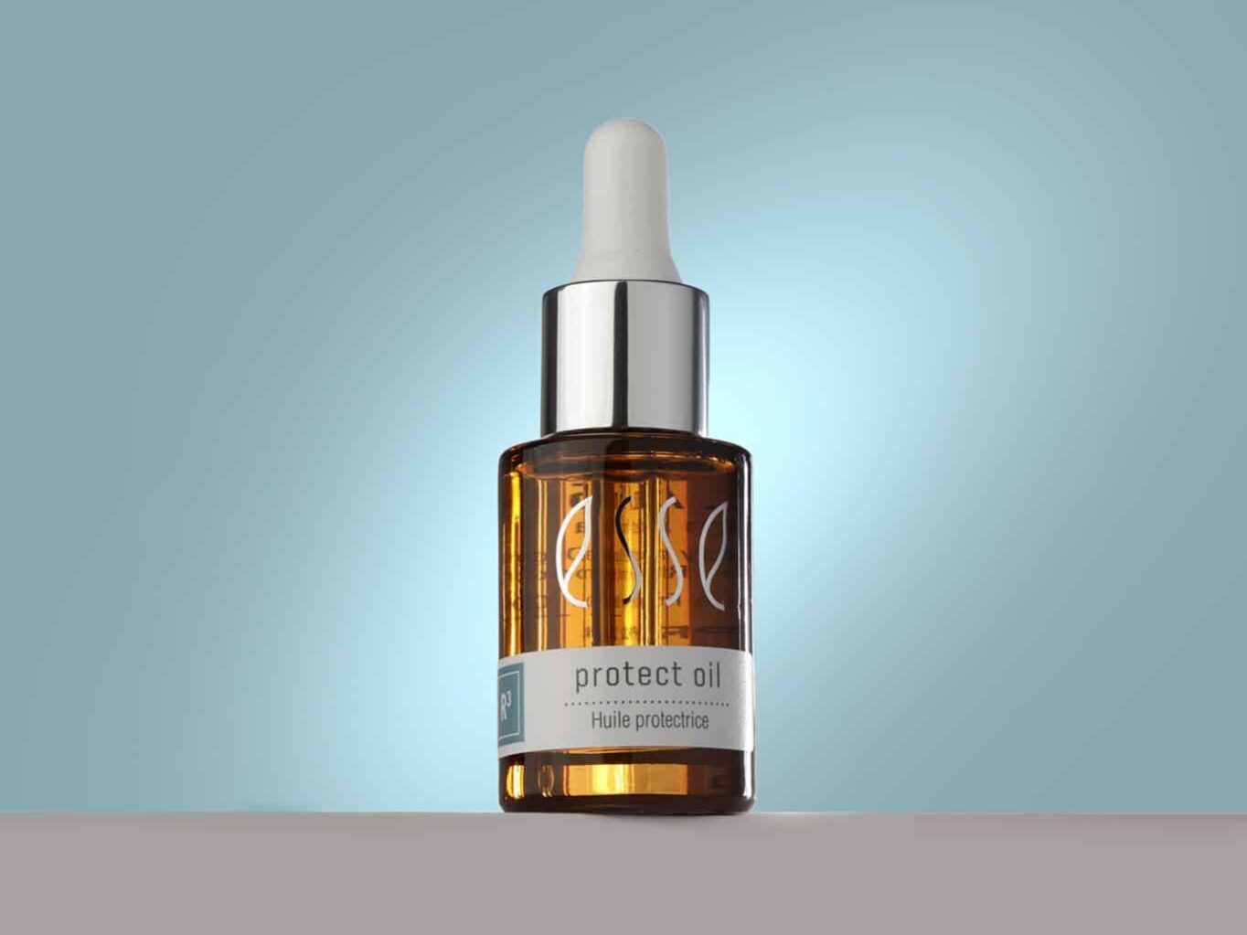 A small amber glass bottle of Esse Protect Oil stands on a neutral surface against a gradient pale blue background. The bottle, with a silver and white dropper cap, features the brand name "Esse" and a label indicating it is protective oil.